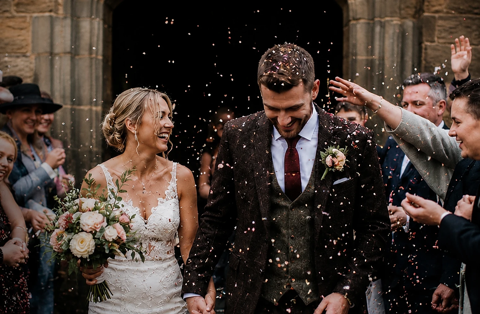 Newly married couple leaving their ceremony through confetti